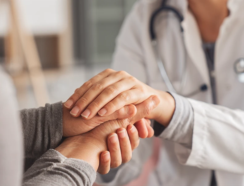 close up of a female doctor holding the hands of a female patient